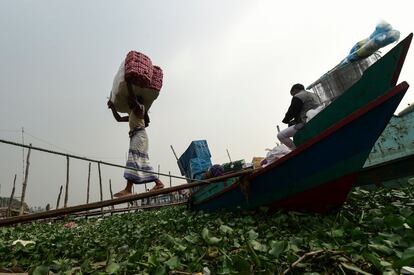 Un trabajador descarga mercancías de un bote a orillas del río Buriganga, en Daca (Bangladés).
