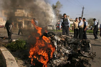 Policías iraquíes observan los restos de uno de los coches bomba que hicieron explosión ayer en Bagdad.