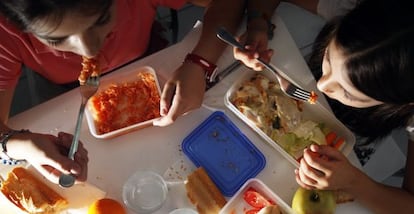 Dos ni&ntilde;as en edad escolar comen comida preparada en casa. 