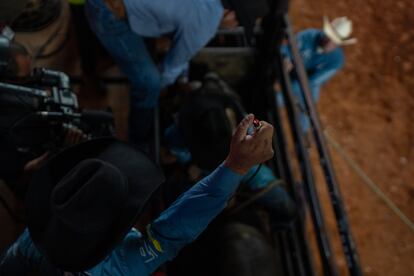 Cowboys get ready to do the traditional bull-riding. Before starting, the announcer recites a prayer, while accompanied by the attendees.