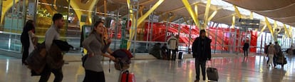 Varios pasajeros pasan ante la zona de acceso al Puente A&eacute;reo, en la terminal 4 de Barajas.