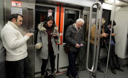 Viatgers del metro de Bilbao consulten el mòbil.