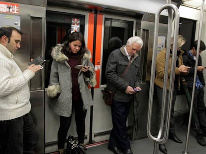 Viatgers del metro de Bilbao consulten el mòbil.