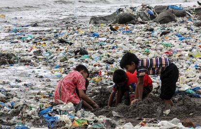 Varios niños juegan entre desechos de comida y plástico cerca de la costa del mar Arábigo, en la playa de Mahim, en Bombay (India).