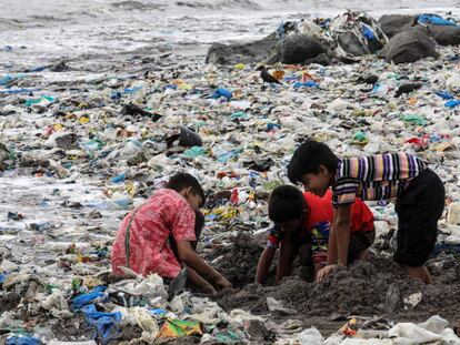 Varios niños juegan entre desechos de comida y plástico cerca de la costa del mar Arábigo, en la playa de Mahim, en Bombay (India).