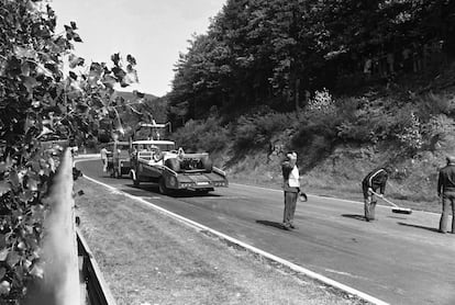 Unos operarios limpian la pista de  Nürburgring y retiran el Hesketh tras el accidente de Lauda. / HANS PETER (AP)