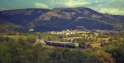 El tren turístico de Felipe II y, al fondo, el Real Sitio de San Lorenzo de El Escorial.