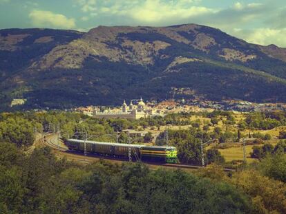 El tren turístico de Felipe II y, al fondo, el Real Sitio de San Lorenzo de El Escorial.