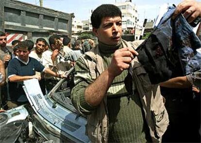 Un palestino de Gaza muestra los restos de ropa encontrados en el lugar donde ayer perecieron seis soldados israelíes.