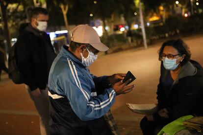 Dos voluntarios entregan un certificado a un sin techo