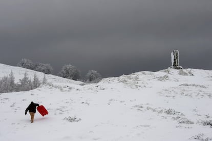 Una persona con su trineo en el Alto de Ibañeta, (Navarra), que ha amanecido nevado debido a la progresiva bajada de la cota de nieve, y que ha hecho que durante la noche se movilicen máquinas quitanieves de forma preventiva.