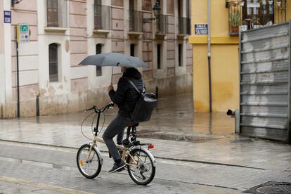 Un ciclista se protege de la lluvia con un paraguas, este jueves en Valencia.