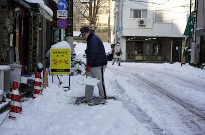 Un hombre despeja la nieve de una acera después de una nevada en Tokio (Japón) el 23 de enero de 2018.