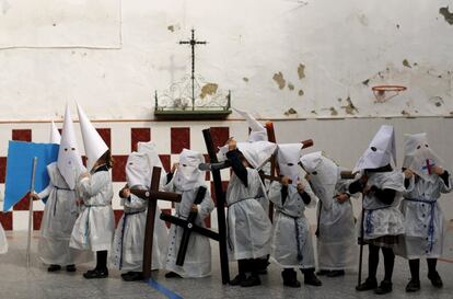 Un grupo de ni?os vestidos de nazarenos se colocan las capuchas despus de participar en una procesin en una escuela de Sevilla.