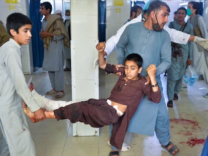 Dos voluntarios llevan a un menor herido tras el ataque en un funeral en Nangarhar, en el este de Afganistán.