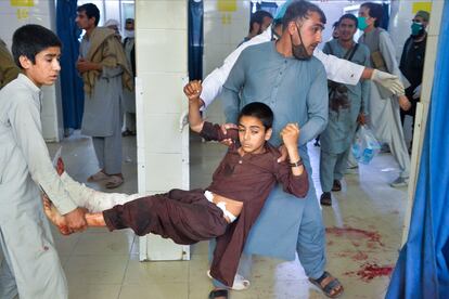 Dos voluntarios llevan a un menor herido tras el ataque en un funeral en Nangarhar, en el este de Afganistán.