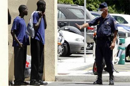 Un policía habla con dos inmigrantes en la comisaría Sur de Tenerife.