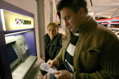 Un hombre observa unos billetes de euros que obtiene de un cajero automático. EFE/Archivo