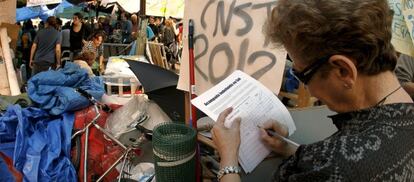 Una mujer deposita su firma en el campamento levantado en la Puerta del Sol de Madrid para apoyar la acampada que se ha organizado.