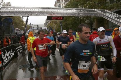 Varios corredores llegan a la meta de la Behobia-San Sebastián, cuya estructura fue derribada por el temporal.