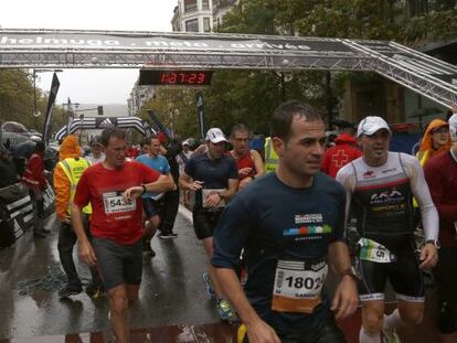 Varios corredores llegan a la meta de la Behobia-San Sebastián, cuya estructura fue derribada por el temporal.