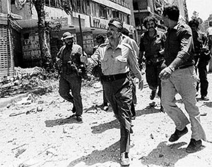 Yasir Arafat en una calle de Beirut, en 1982, tras un bombardeo israelí.