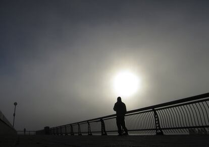 Un hombre corre por un muelle de Hoboken (Nueva Jersey) bajo un sol que asoma entre la niebla que cubre el cielo de Nueva York.