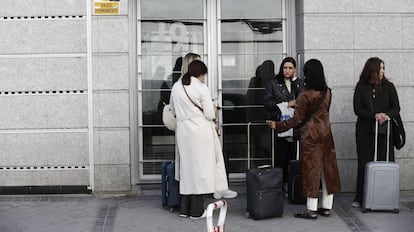 Varias personas esperan en el portal de un edificio con pisos de alquiler para uso turístico, en Madrid.