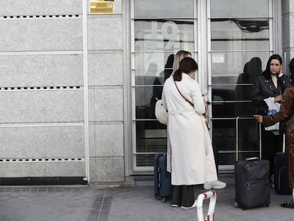 Varias personas esperan en el portal de un edificio con pisos de alquiler para uso turístico, en Madrid.