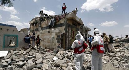 Trabajadores de la Media Luna Roja y civiles inspeccionan el lugar del bombardeo, este mi&eacute;rcoles al norte de San&aacute;.