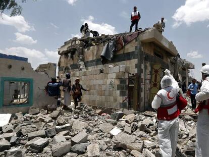 Trabajadores de la Media Luna Roja y civiles inspeccionan el lugar del bombardeo, este mi&eacute;rcoles al norte de San&aacute;.