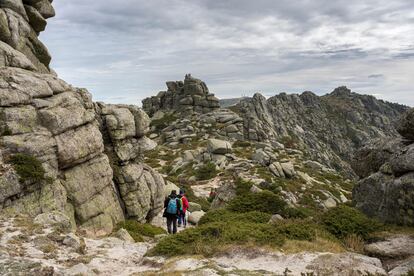 Senderistas siguiendo la ruta de los Siete Picos, de las formaciones más singulares de la sierra de Guadarrama.