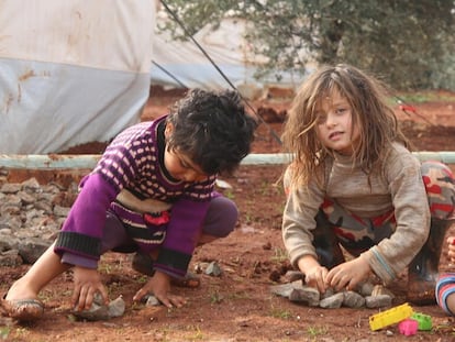 Dos niñas juegan con juguetes cerca de su tienda en el noroeste de Siria.