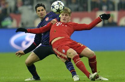 Arteta y Kroos pugnan por un bal&oacute;n.