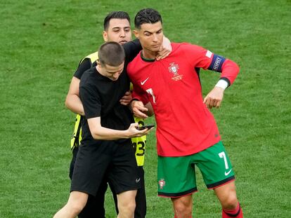 A fan who ran onto the pitch holds on to Portugal's Cristiano Ronaldo during a Group F match between Turkey and Portugal at the Euro 2024 soccer tournament in Dortmund, Germany, Saturday, June 22, 2024. (AP Photo/Michael Probst)