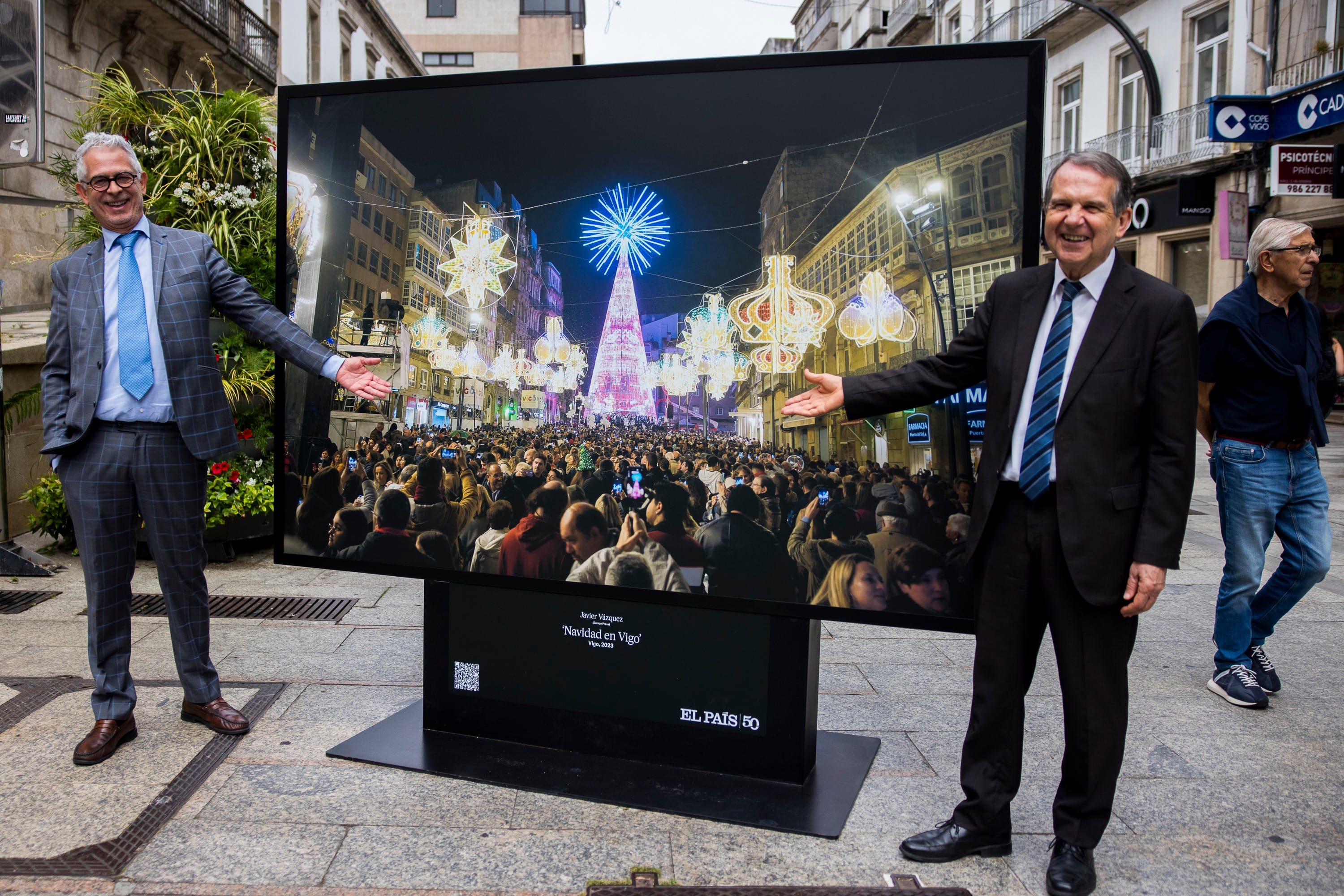Javier Moreno, exdirector de EL PAÍS y comisario del 50º aniversario (izquierda) posa ante la fotografía de la Navidad en Vigo junto al alcalde de la ciudad, Abel Caballero, este lunes. 
