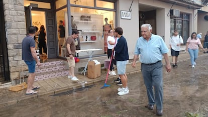 Varias personas limpian el barro de la calle, tras las lluvias del viernes en Tarazona (Zaragoza).