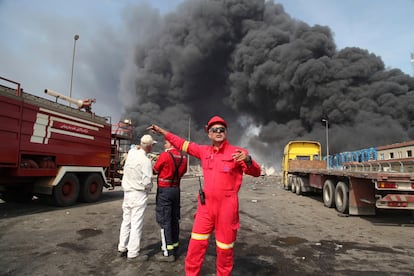 Varios bomberos partcipan en las labores de extinción del incendio que se ha originado en el puerto de Bandar Abbas tras la fuerte explosión.