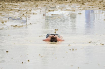 Una mujer permanece tumbada en el barro después de la enorme tromba de agua caída el pasado sábado sobre el desierto en que se celebra el Burning Man. 
