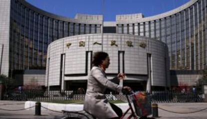 Una mujer pasa frente a la sede del Banco Popular de China, en Pek&iacute;n. 