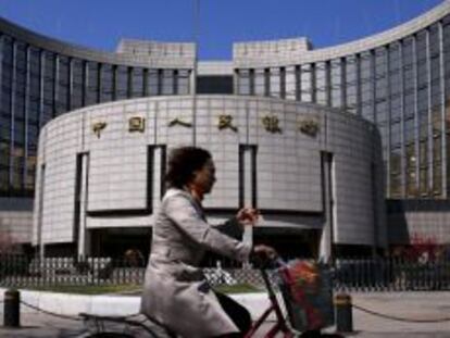 Una mujer pasa frente a la sede del Banco Popular de China, en Pek&iacute;n. 