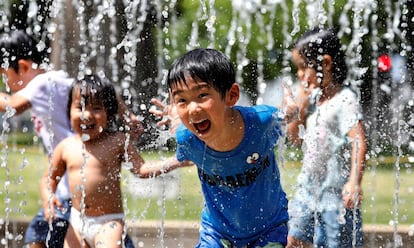 Varios niños juegan en los chorros de agua de una fuente en un parque cerca de Nerima, en Tokio, Japón, el 23 de julio de 2018.