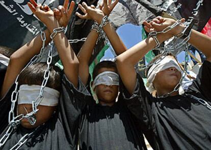 Tres niños con las manos encadenadas y haciendo el signo de la victoria, ayer en la manifestación en Gaza.