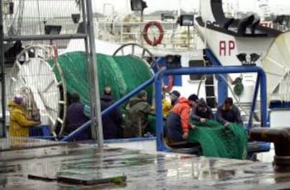 Pescadores de un barco atracado en el puerto de Gijón realizan labores de mantenimiento al encontrarse amarrada la flota pesquera a causa del temporal de viento y lluvia. EFE/Archivo