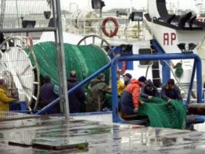Pescadores de un barco atracado en el puerto de Gijón realizan labores de mantenimiento al encontrarse amarrada la flota pesquera a causa del temporal de viento y lluvia. EFE/Archivo