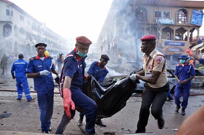 Personal de emergencias rescatan el cadáver de una persona tras un atentado en una zona comercial en Abuja (Nigeria).