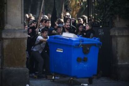Un grupo de manifestantes utiliza como barricada un contenedor de basura en Barcelona.
