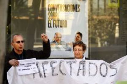 Un impositor de la CAM muestra un euro mientras se manifiesta con otros afectados a las puertas de una sucursal del Banco de Sabadell. EFE/Archivo
