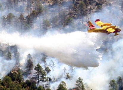 Un avión descarga agua sobre un bosque durante las tareas de extinción del incendio de Aliaga (Teruel).