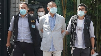 Hong Kong media tycoon Jimmy Lai, center, is arrested by police officers at his home in Hong Kong, August 10, 2020.